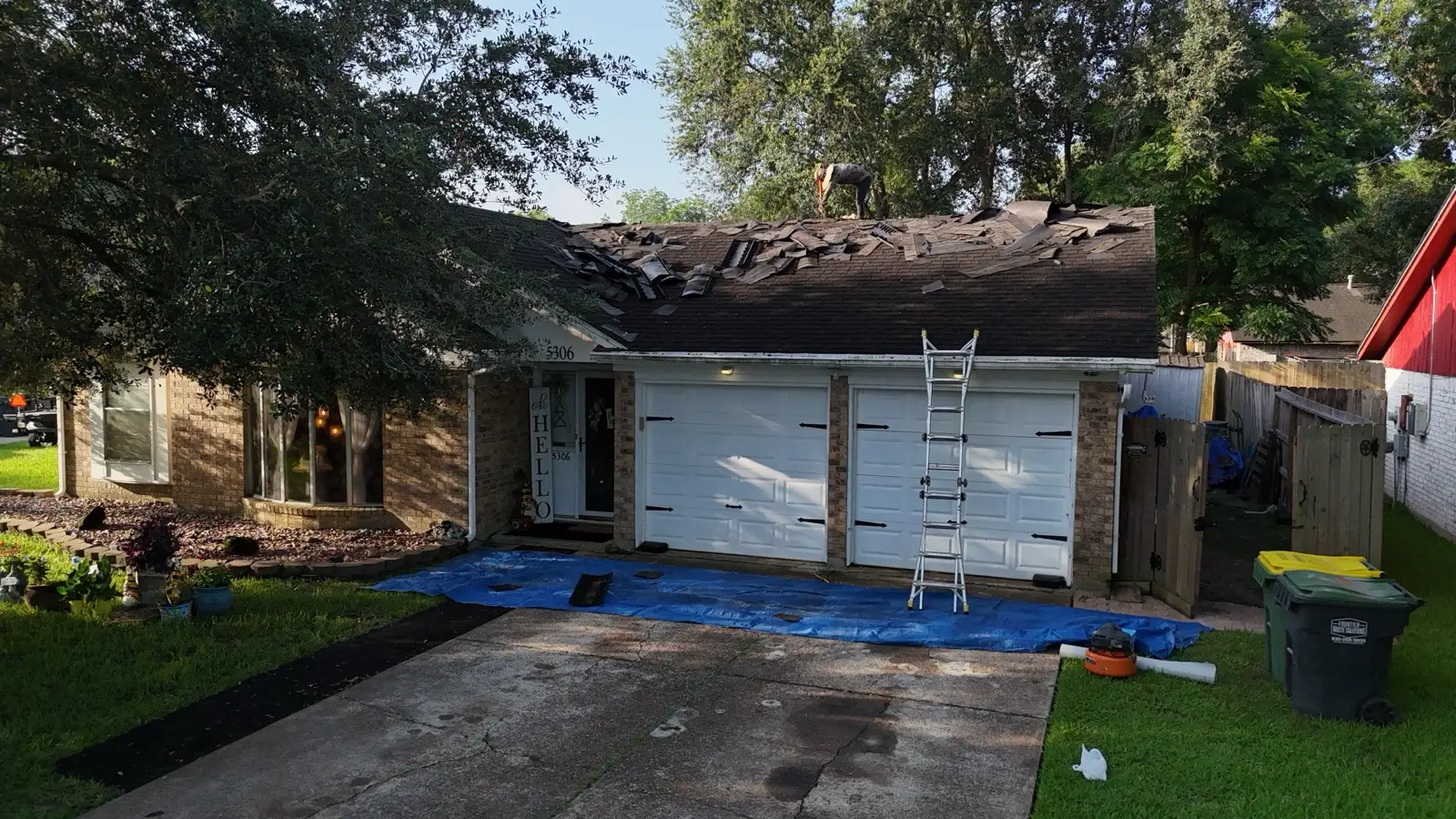 June 19, morning. Tear-off underway — tarps over the driveway and flowerbeds first.