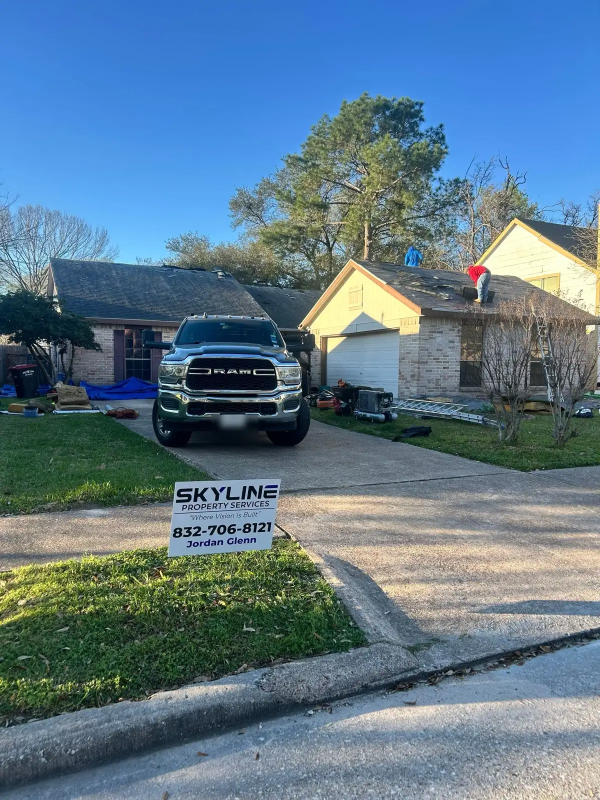 February 23, morning. Build day underway — tear-off already moving on the roof behind the yard sign.