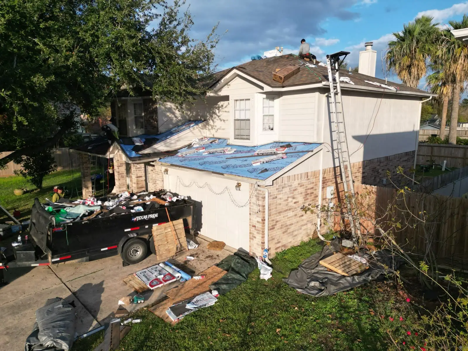 December 18. Mid-build from the corner of the lot — the trailer taking the old roof, the deck papered and dried in.