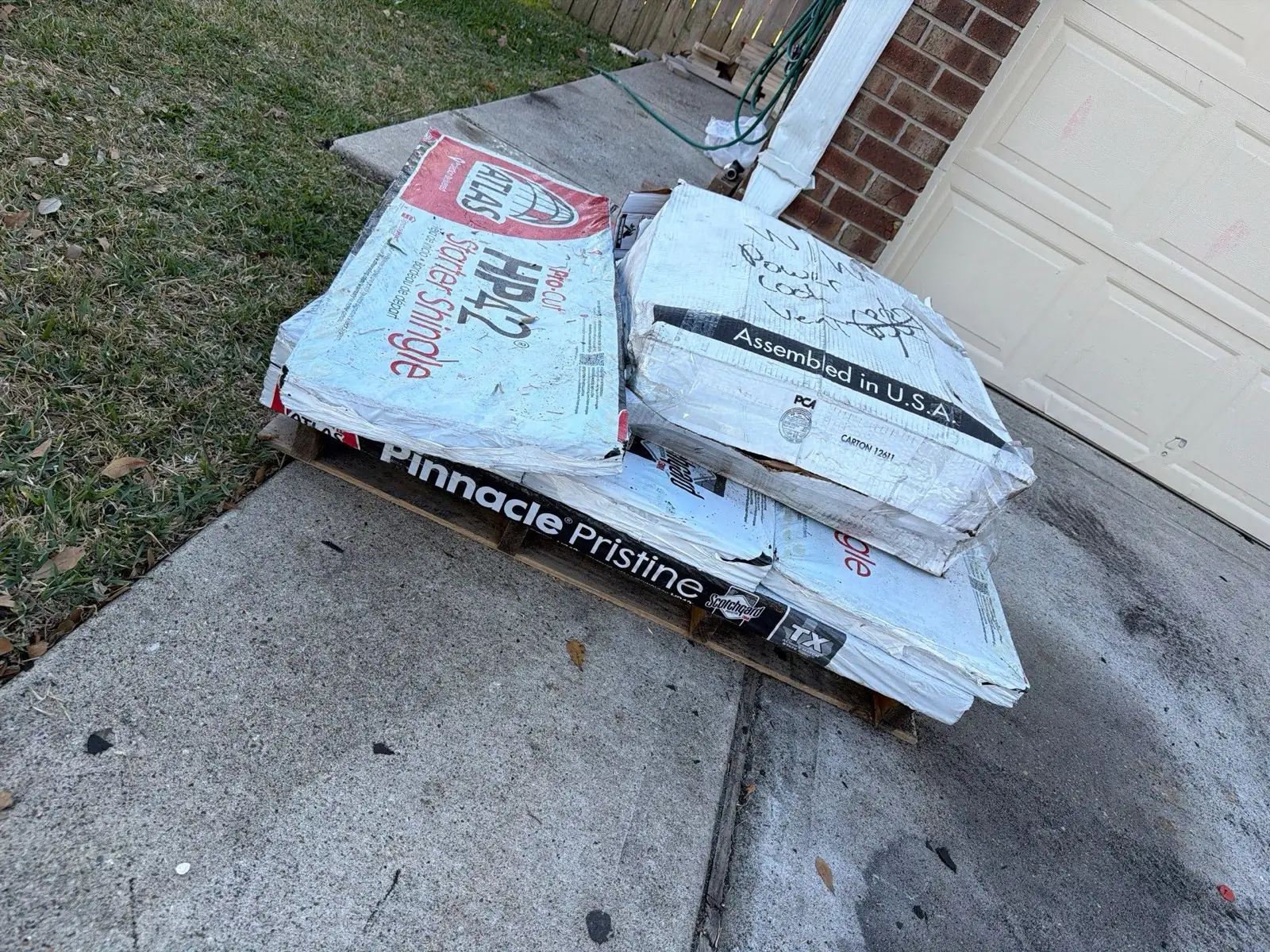 December 30. The spec on the driveway — Atlas Pinnacle Pristine wrappers and matching starter on the pallet.
