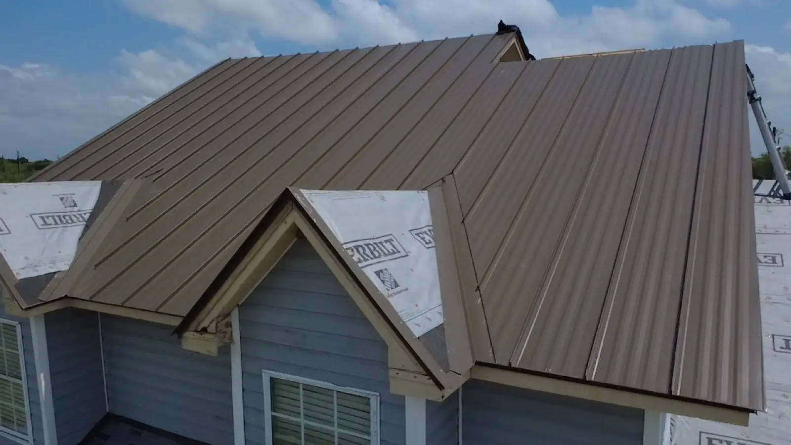 May 19. Brown standing-seam going over the dormers, underlayment at the flanks.