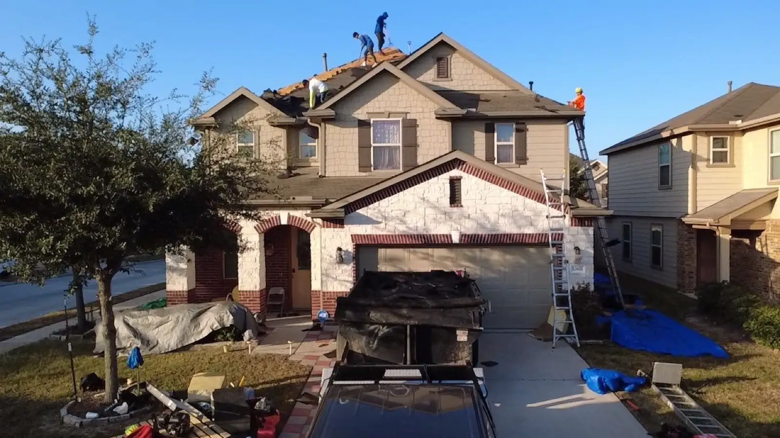 November 18. The crew across the roof, tarps over the landscaping, trailer backed to the garage.