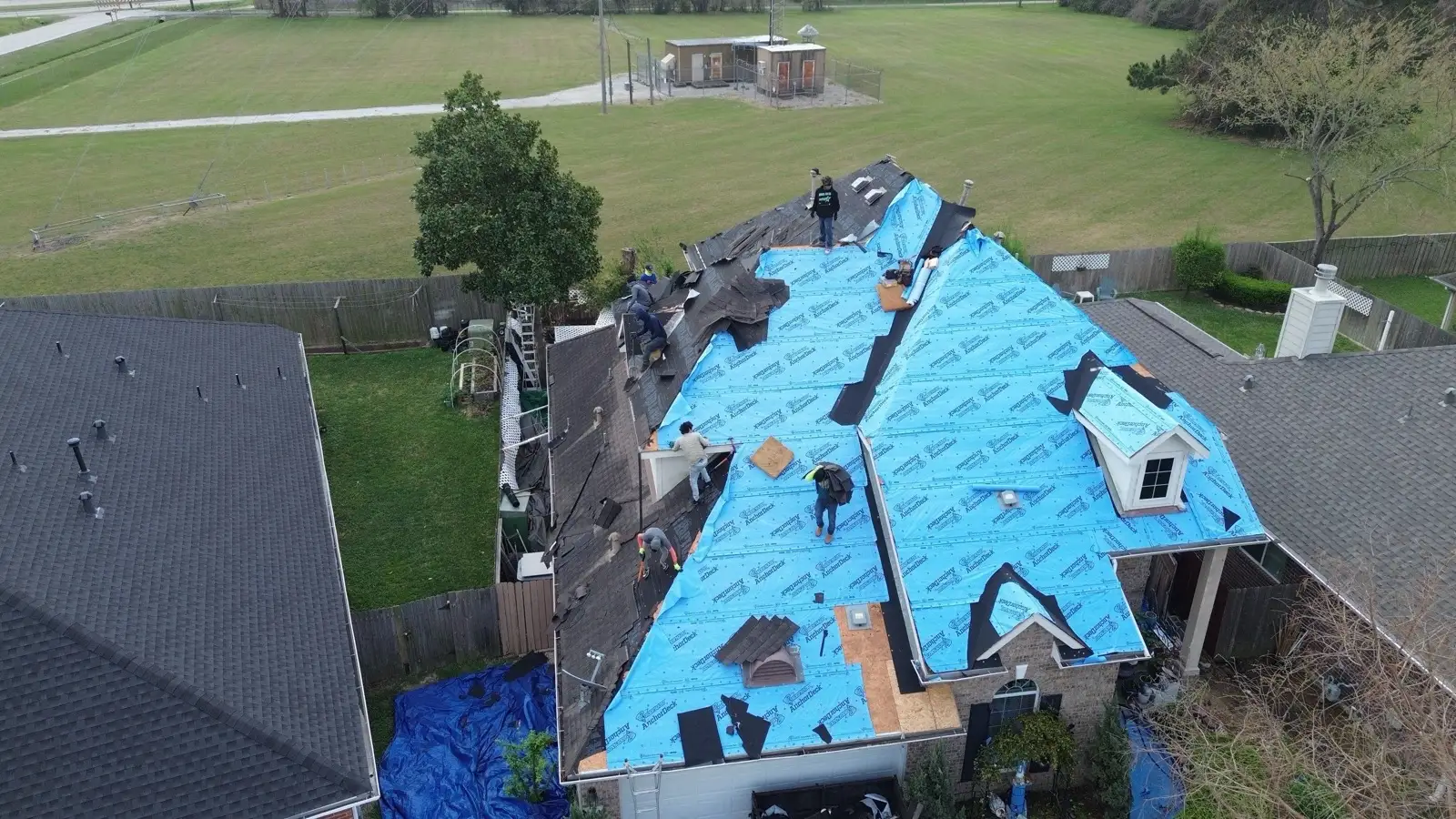 March 3. The old shingles coming off ahead of the blue underlayment, crew working both slopes.