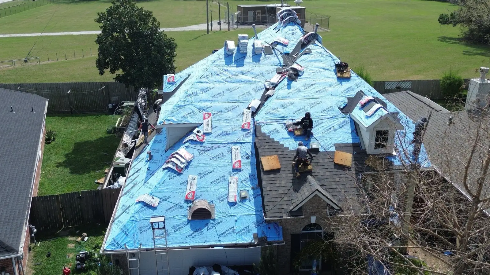 March 3. The whole deck sealed in underlayment, labeled shingle bundles staged on the slopes.